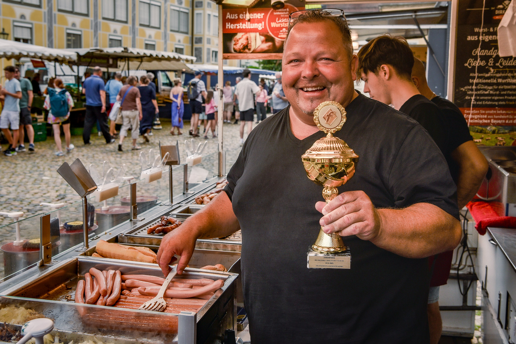 Dirk Licht mit Pokal am Wurststand beim Markt