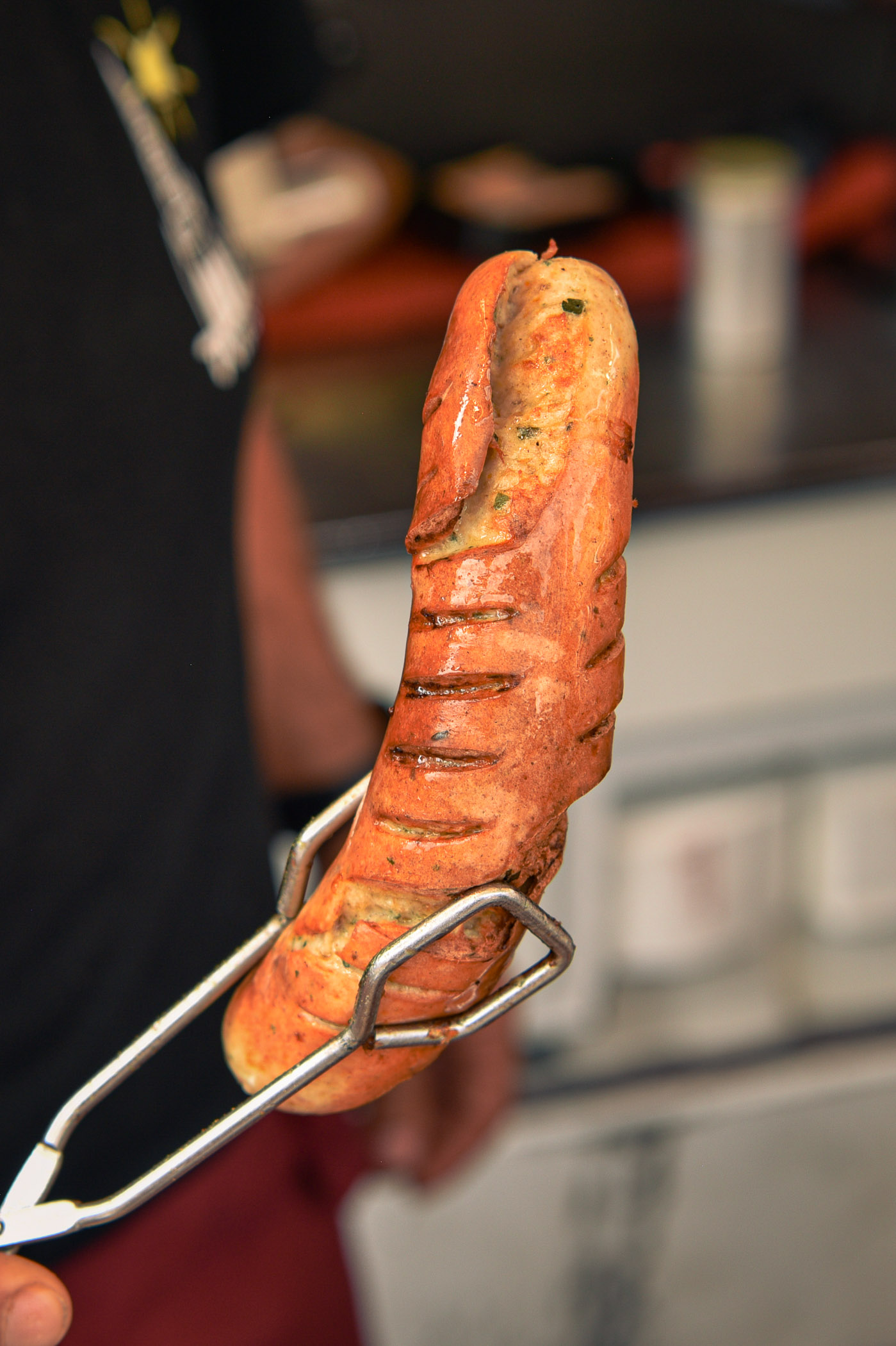 Frische Bratwurst mit Kräutern auf Grillzange